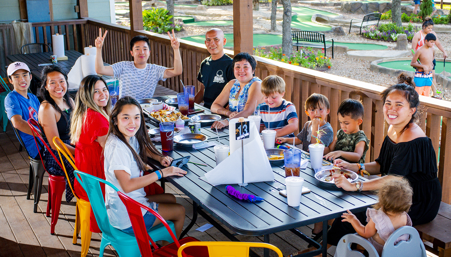 BLOG A group of people of various ages sitting around a large table outdoors, sharing a meal.